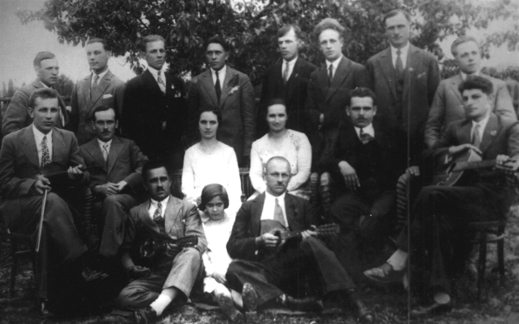 Józef Twaróg ze swym ulubionym instrumentem - skrzypcami (siedzi na krześle pierwszy z lewej) wraz z członkami zespołu muzycznego. W centrum na trawie siedzi ówczesny kierownik szkoły w Księżomierzu - Julian Mazepa. Księżomierz I połowa lat 30-tych XX wieku.