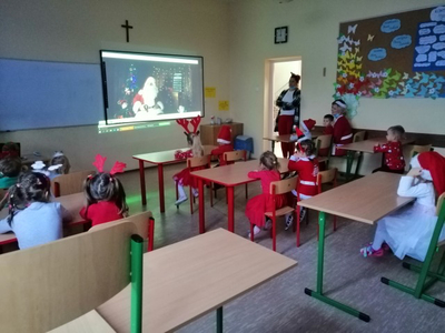 Dzieci oglądają Mikołaja na ekranie.