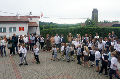 Zdjęcie przedstawiające zgromadzonych. W centrum dzieci, ustawione w pary tańczą poloneza
