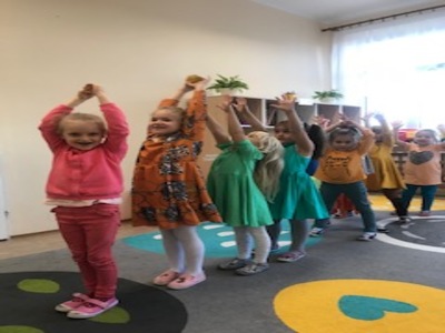 Dziewczynki stoją z uniesionymi rękami w górze.