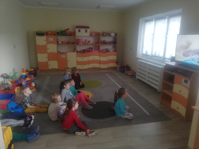 Dzieci siedzą na dywanie, oglądają bajkę edukacyjna