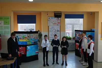 Zdjęcie przedstawiające uczniów prowadzących apel. Z prawej strony poczet flagowy.