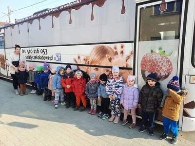 Dzieci pozują do zdjęcia na tle autobusu.
