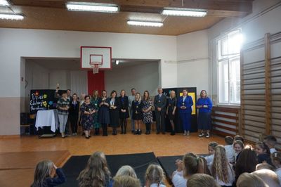 Grupa nauczycieli i pracowników obsługi ze statuetkami i medalami.