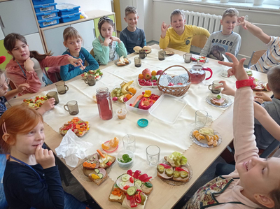 Zdjęcie roześmianych uczniów siedzących przy stole.