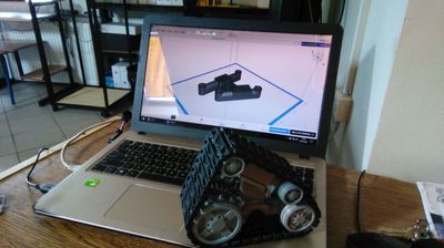 Zdjęcie laptopa z otwartym plikiem podzespołu. Na laptopie zmontowany system napędowy robota.