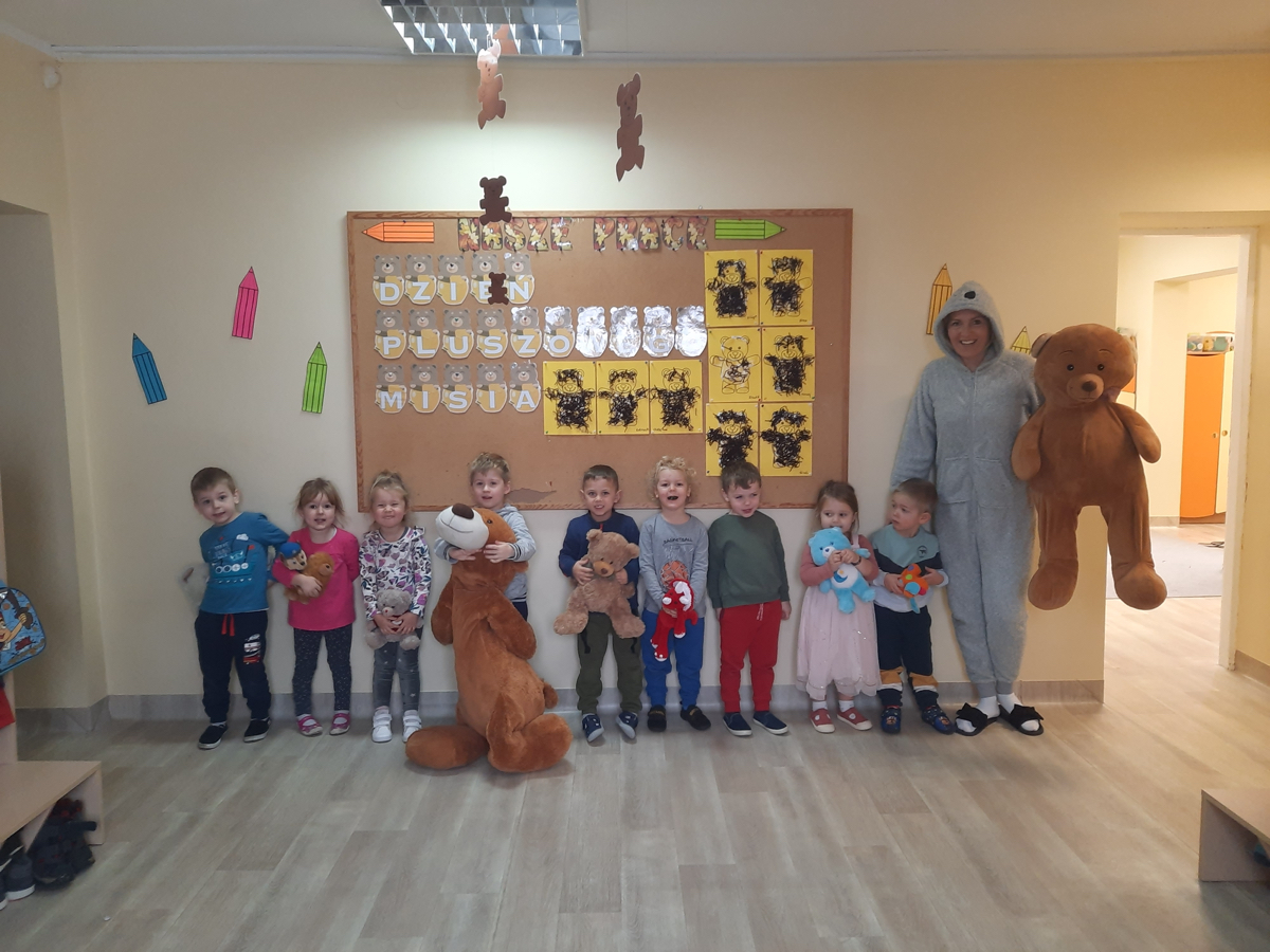 Grupa 3,4 - latków na tle tablicy.