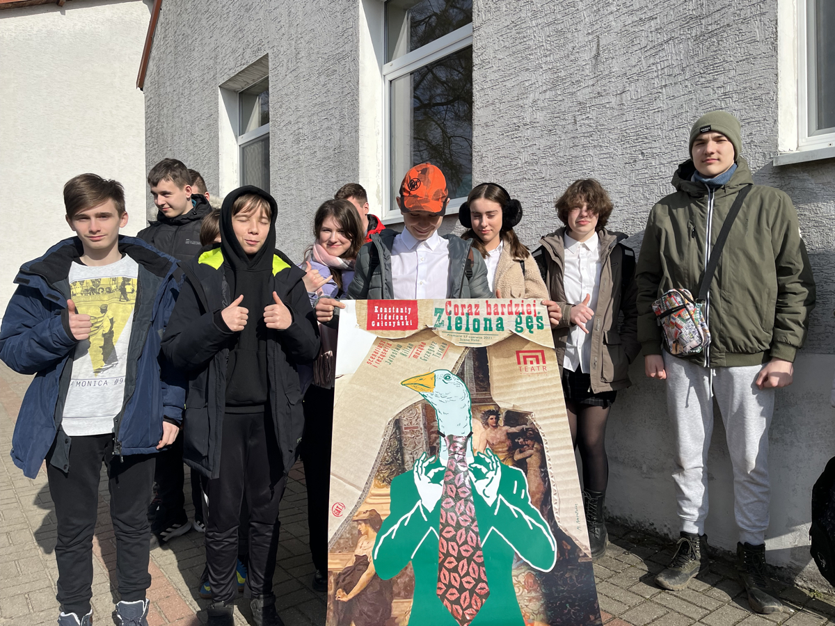 Grupa uczniów z plakatem sztuki pod tytułem "jeszcze bardziej zielona gęś"