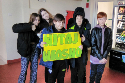 Grupka uczniów trzymająca transparent z napisem: witaj wiosno.