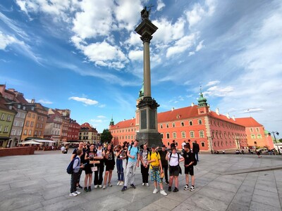 Grupa uczniów stojąca przy Kolumnie Zygmunta w Warszawie. W tle Zamek Królewski.