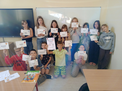 Grupa dzieci trzymających w dłoniach kartki.