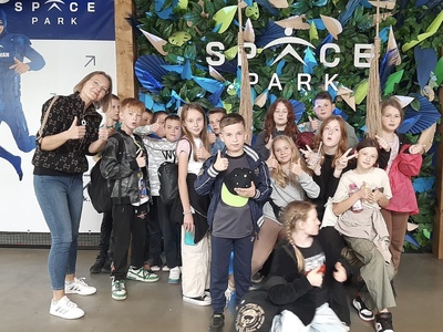 Uczniowie wraz z wychowawcą stoją przy ściance z napisem Space Park.