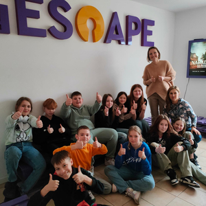 Grupka dzieci z opiekunami, na ścianie napis iescape.