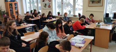 Grupa uczniów siedzących przy ławkach w sali lekcyjnej.