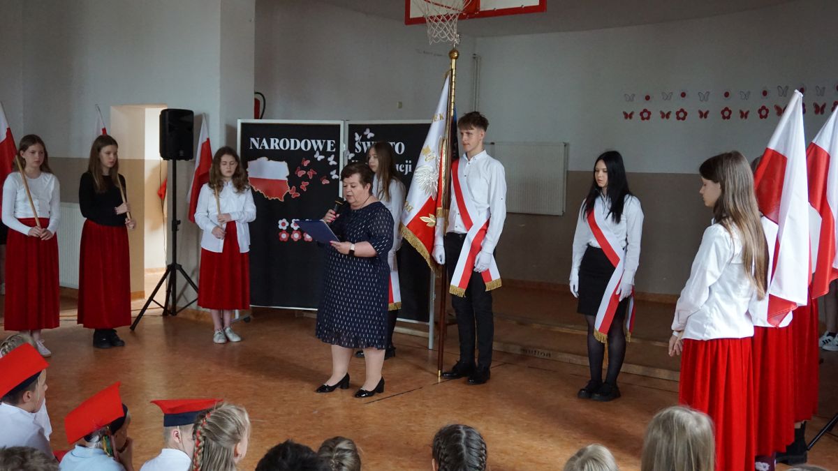 Przemówienie pani Dyrektor, w głębi poczet sztandarowy szkoły.