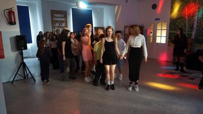 Grupa uczniów na parkiecie przygotowująca się do wspólnego tańca.