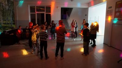 Grupa uczniów stojących w okręgu podczas zabawy taneczno-wokalnej.