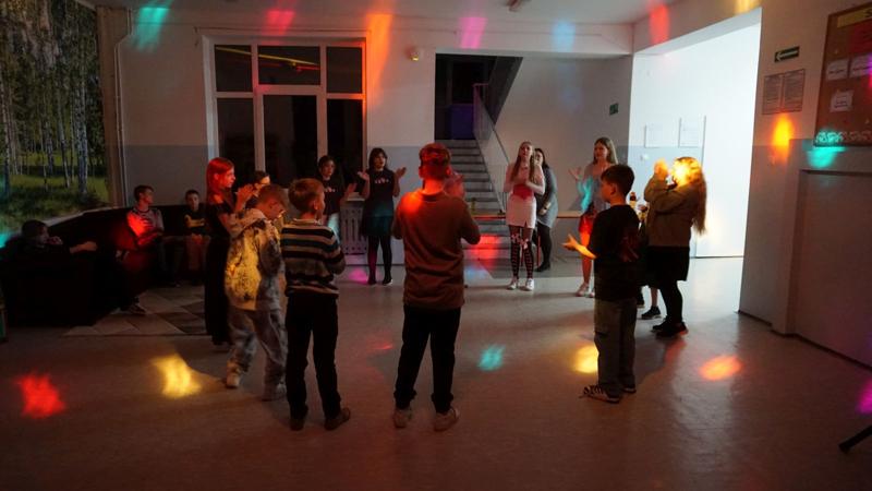 Grupa uczniów stojących w okręgu podczas zabawy taneczno-wokalnej.