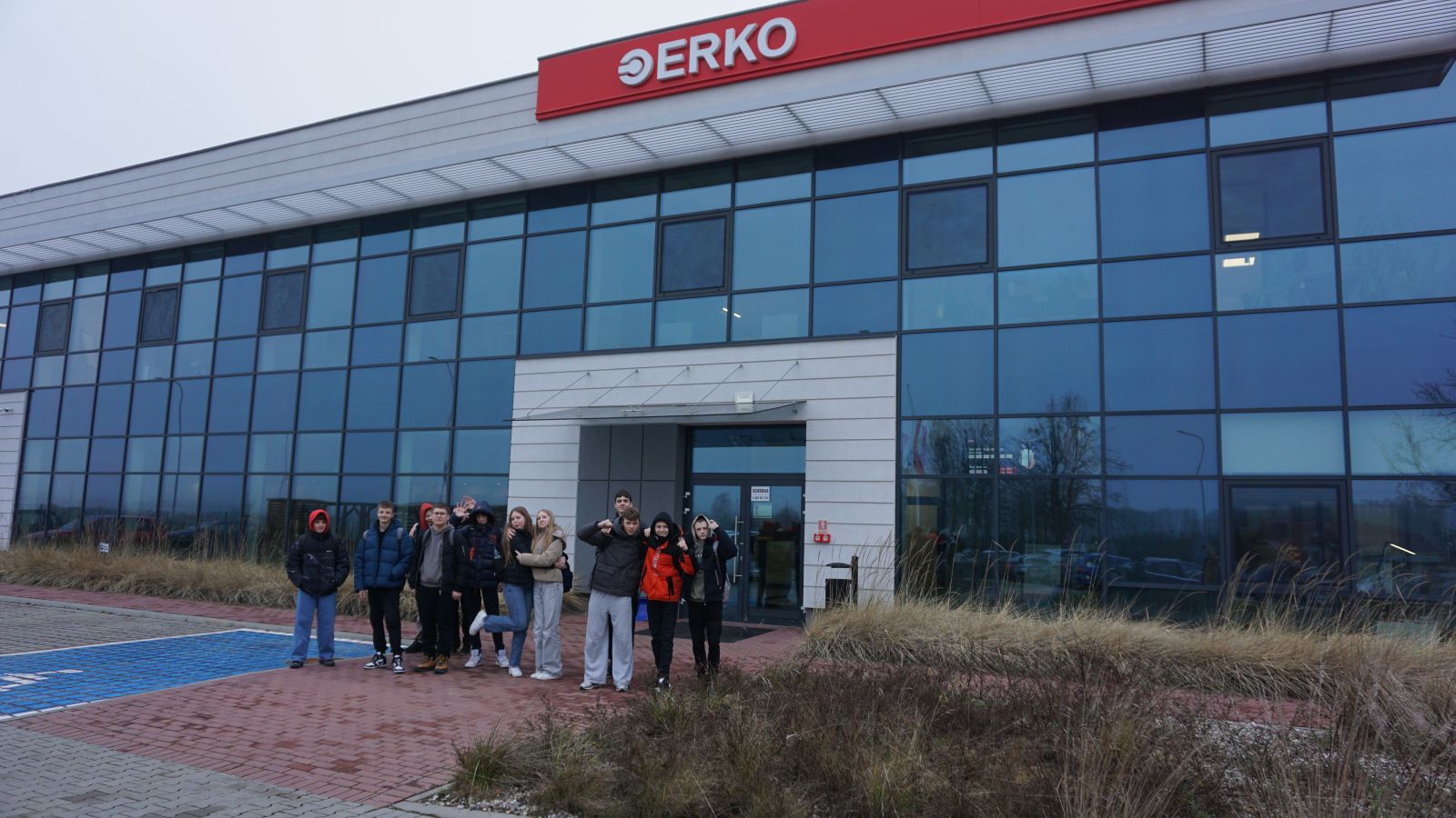 Grupa uczniów stojąca przed wejściem do budynku formy Erko.