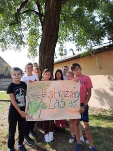 Uczniowie na tle drzewa z banerem "Strażnicy lasu"