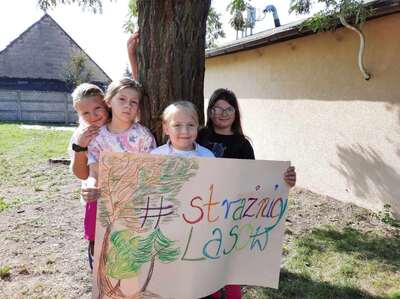 Uczniowie na tle drzewa z banerem "Strażnicy lasu"