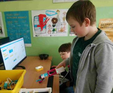 Chłopcy pokazują, jak działa chwytak, którego złożyli z klocków Lego, a potem zaprogramowali.