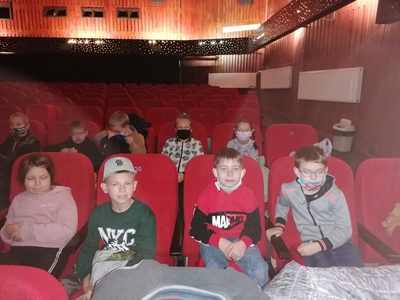 Wyjazd uczniów klas 0 - III szkoły podstawowej do kina. Zdjęcie grupowe uczniów na sali kinowej.