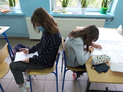 Uczestnicy projektu uczą się współpracy pomiędzy sobą - siedzą plecami do siebie. Jedna osoba odczytuje rysunek i instruuje drugą, rysującą osobę.