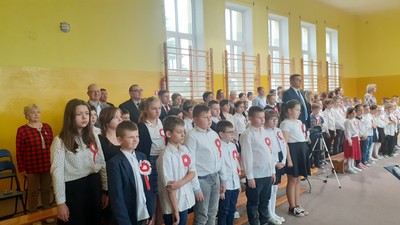 Uczniowie, nauczyciele i goście w trakcie wykonywania hymnu państwowego