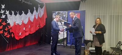 Uczeń szkoły odbiera dyplom za udział w przeglądzie