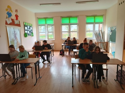 UCZNIOWIE ROZWIĄZUJĄ ZADANIA PRZY ŁAWKACH 