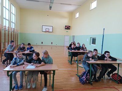 UCZNIOWIE ROZWIĄZUJĄ ZADANIA PRZY ŁAWKACH 