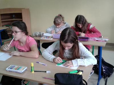 Grupa dzieci piszących na kartkach.