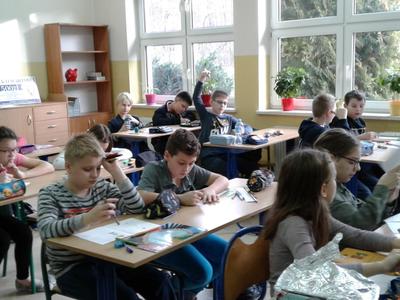 Zdjęcie klasy uczniów jeden z podniesioną ręką.