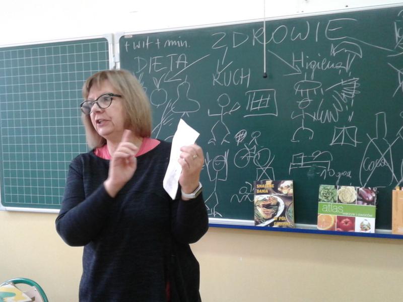 Zdjęcie osoby. Nauczycielka sto przed tablicą w klasie.