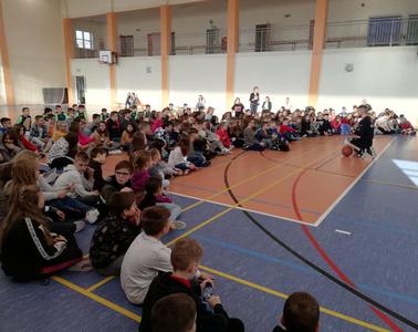 Hala wypełniona siedzącymi uczniami, przed nimi trener