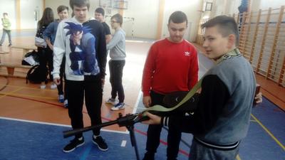 Chłopiec trzymający karabin. Obok dwóch chłopców.