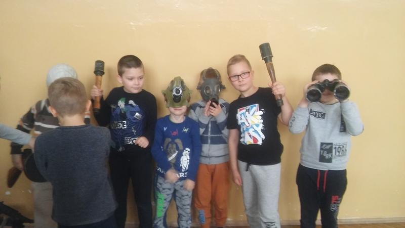 Zdjęcie. Grupa dzieci prezentuje sprzęt wojskowy.