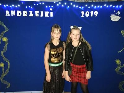 Dwie dziewczynki na tle niebieskiej ściany z napisem andrzejki 2019