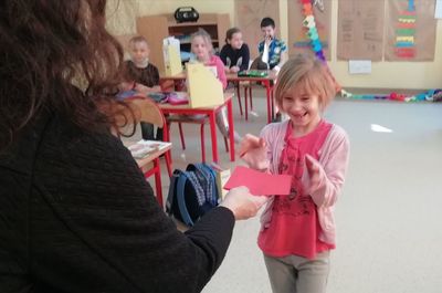 Dziewczynka odbiera czerwoną kartkę od nauczyciela