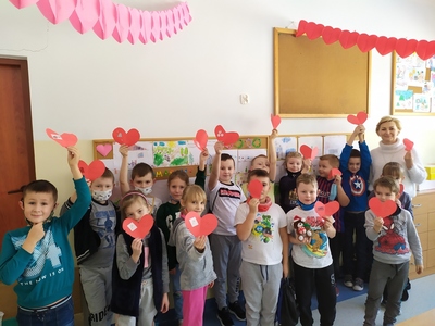 Grupa dzieci trzymające czerwone serduszka