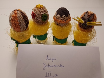 Napis Alicja Jakubowska, obok cztery pisanki ozdobione ziarnami.