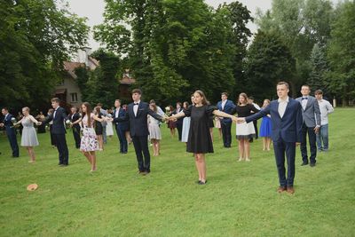 Kilka par tańczących poloneza trzymająca się szeroko za ręce