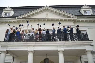 Uczniowie na balkonie rzucają do góry birety