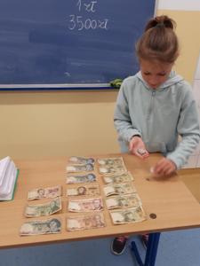 Uczennica prezentująca banknoty sprzed denominacji.