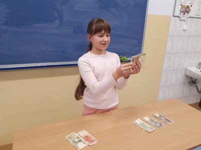 Uczennica trzymająca banknot sprzed denominacji.