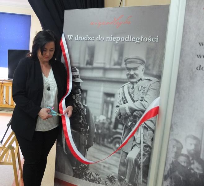 Wójt Gminy przecinająca wstęgę i otwiera wystawę.
