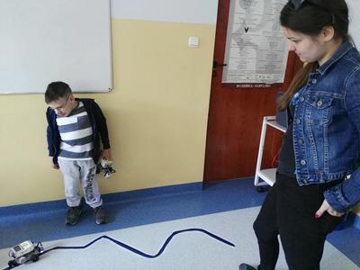 Dziecko oraz kobieta patrząca na robota który jedzie po linii