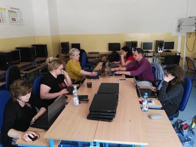 Ludzie siedzący przy stole. Przed nimi laptopy.