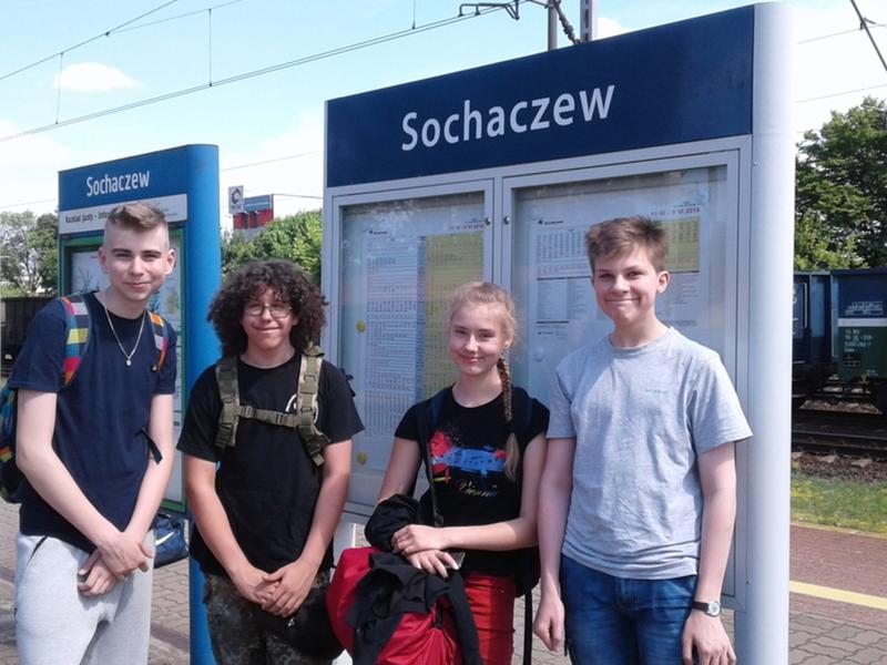Uczestnicy czekający na pociąg na peronie kolejowym.